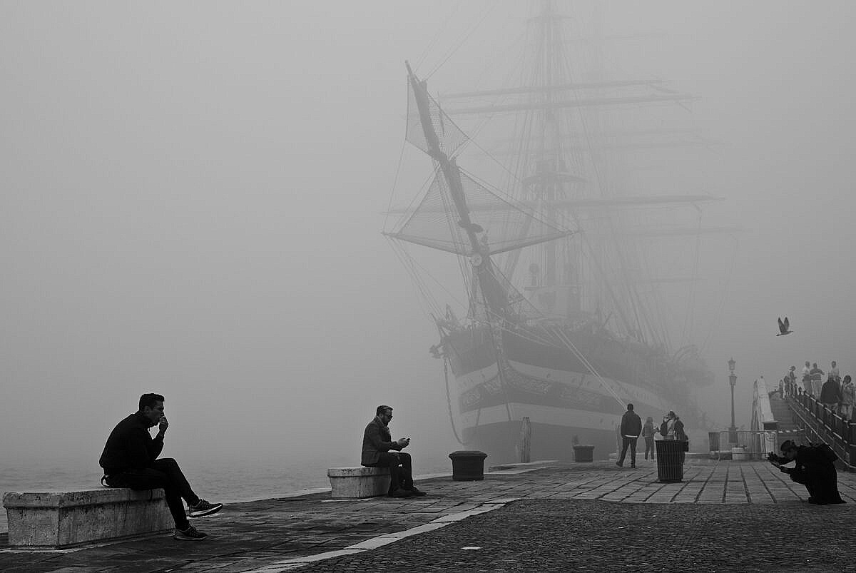 Tall ship Amerigo Vespucci in Venice on a foggy day, with people in the foreground