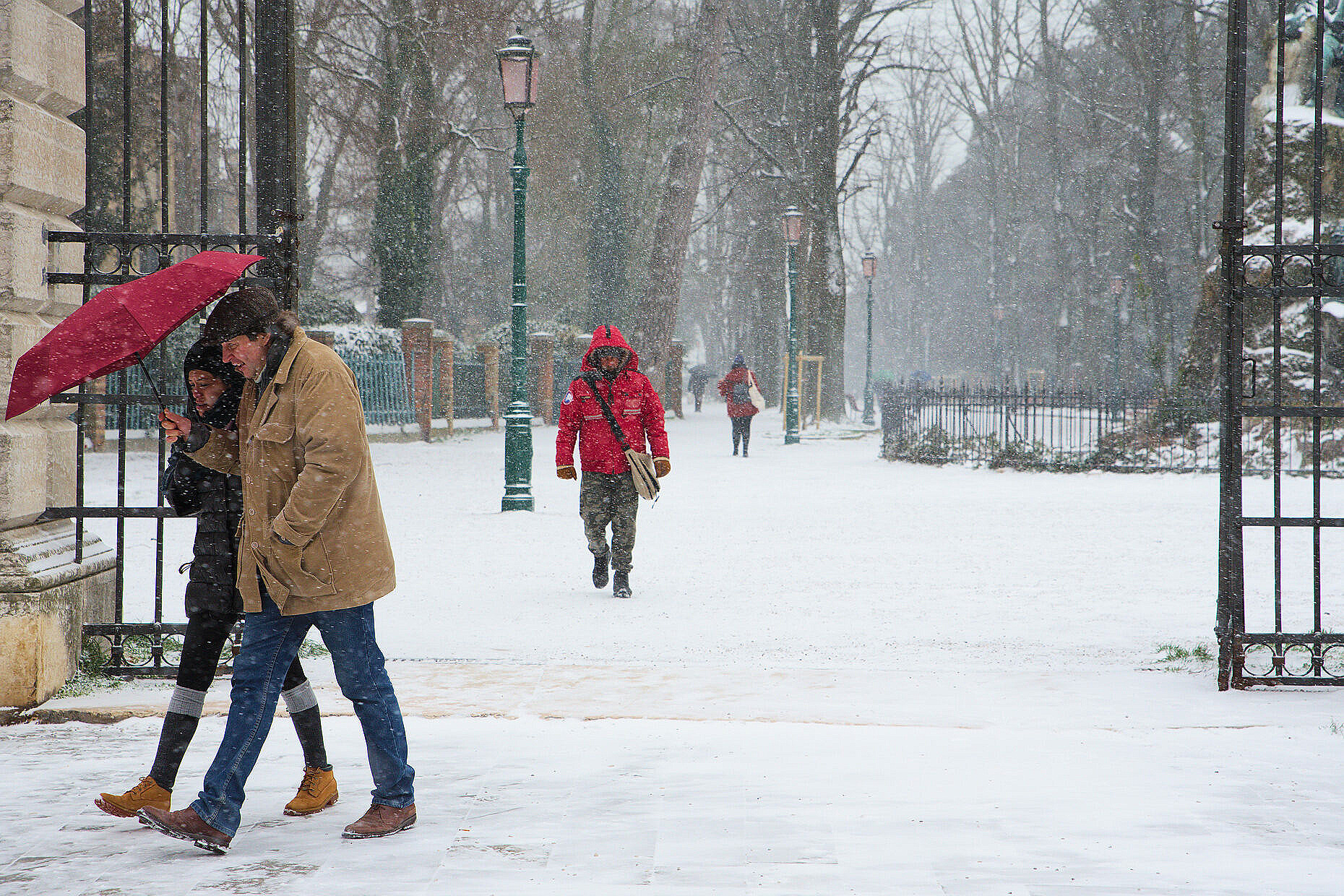People walking huddling together under an umbrella in the snow in Via Garibaldi.