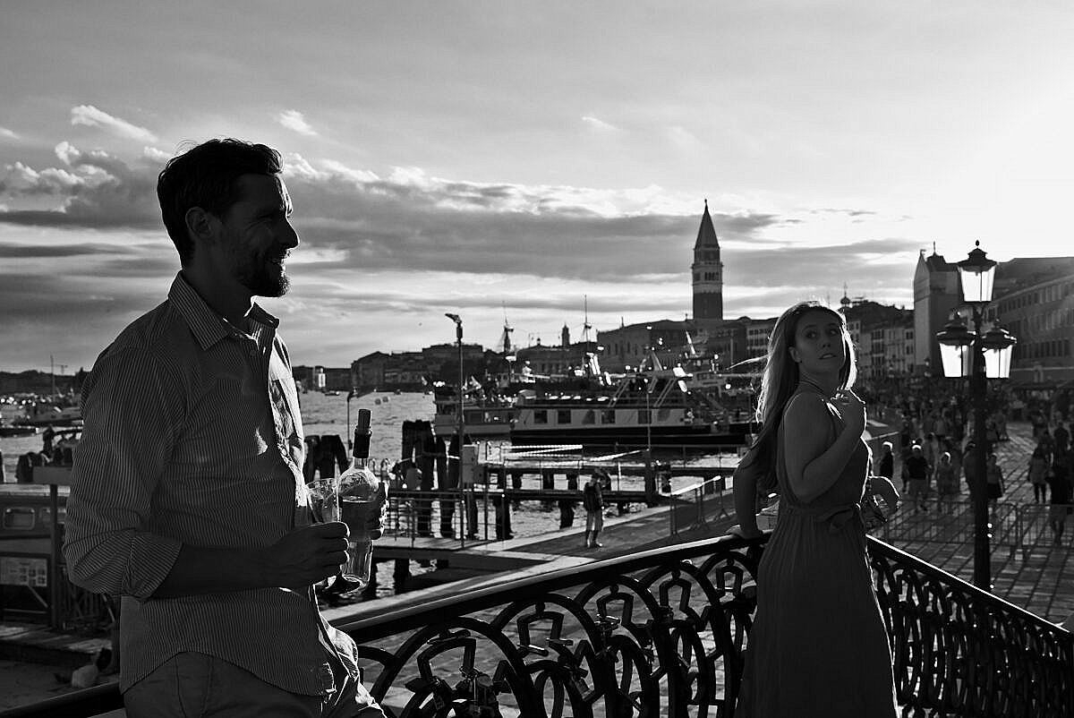 A woman glancing at a man on a bridge in Venice during the Redentore Feast in July